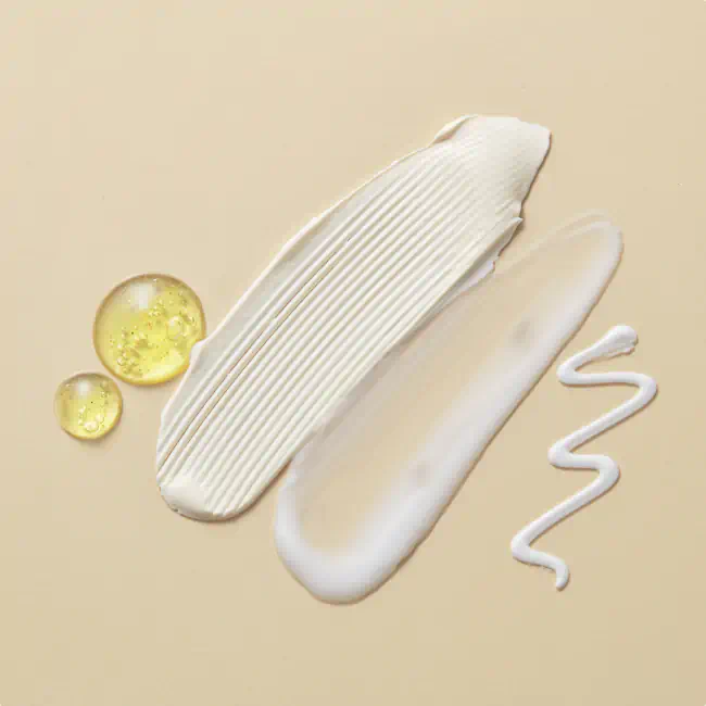 Swatches of cream, lotion, gel, and oil on a beige surface