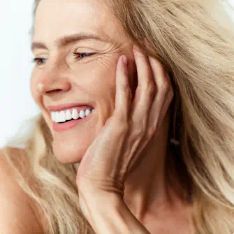 Joyful mature woman with long blonde hair smiling and looking to the side
