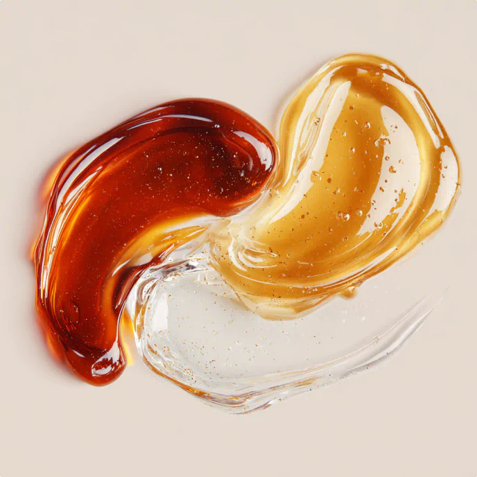 Swirls of amber, golden, and clear gel textures on a neutral surface